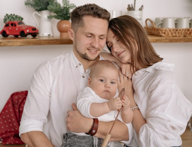 A joyful family of three embracing in a cozy kitchen. Warm and loving atmosphere.